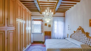 Un dormitorio con una cama grande, un armario de madera y una araña.