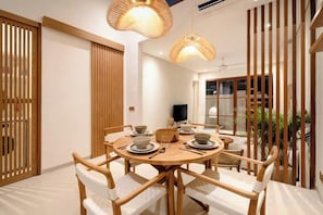 A dining area with a round table, chairs, and hanging lights.