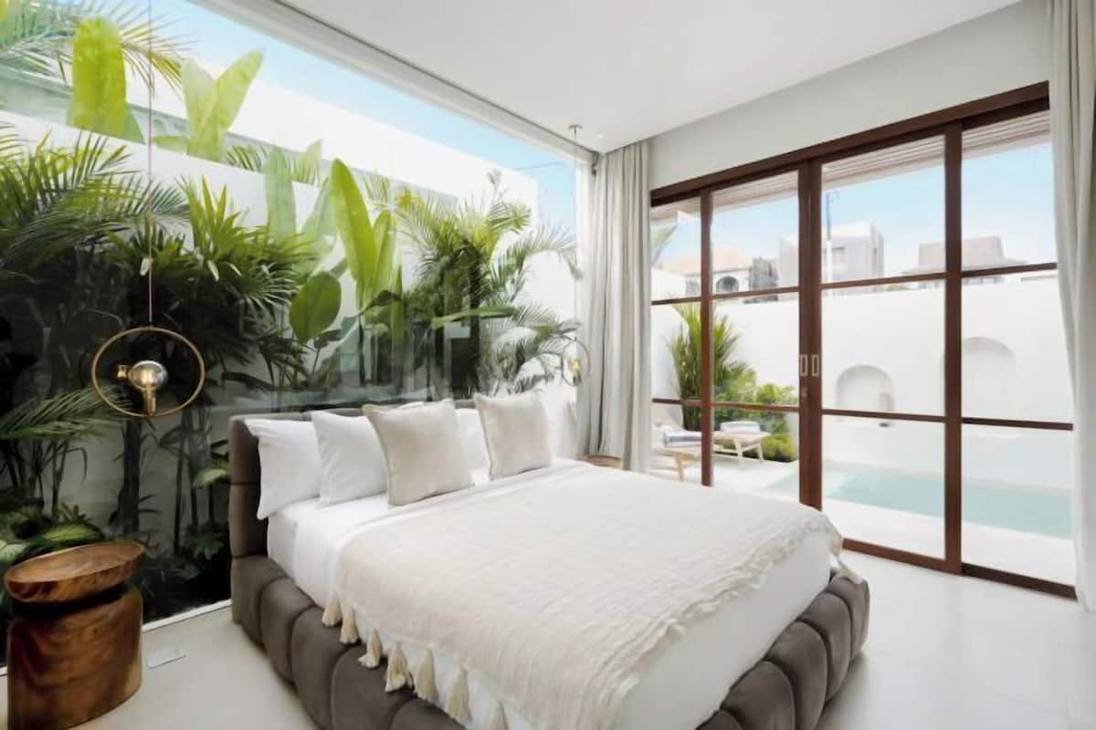 Een moderne slaapkamer met een groot bed, uitzicht op de omgeving en een balkon met een zwembad.
