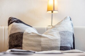En seng med to puder og en lampe i baggrunden.
