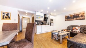 A modern living room with a dining area, a kitchen, and a sofa.