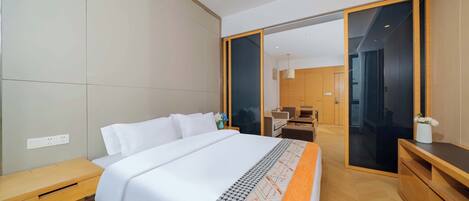 A modern hotel room with a large bed, wooden flooring, a desk, and a wardrobe.