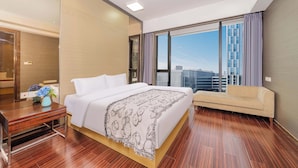 A modern hotel room with a large bed, a sofa, a desk, and a view of the cityscape through large windows. - Xilaideng Guangzhou Service Apartment (Guangzhou)