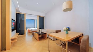 A modern hotel room with a wooden floor, a sofa, a dining table, and a TV. - Xilaideng Guangzhou Service Apartment (Guangzhou)