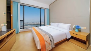 A modern hotel room with a large bed, wooden nightstands, a desk, and a view of a cityscape through a large window. - Xilaideng Guangzhou Service Apartment (Guangzhou)