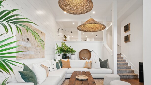 Ein modernes Wohnzimmer mit einem weißen Sofa, einem Holztisch und einer Treppe, die zu einer oberen Ebene führt.