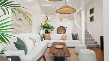 A modern living room with a white sofa, a wooden coffee table, and a staircase leading to an upper level.
