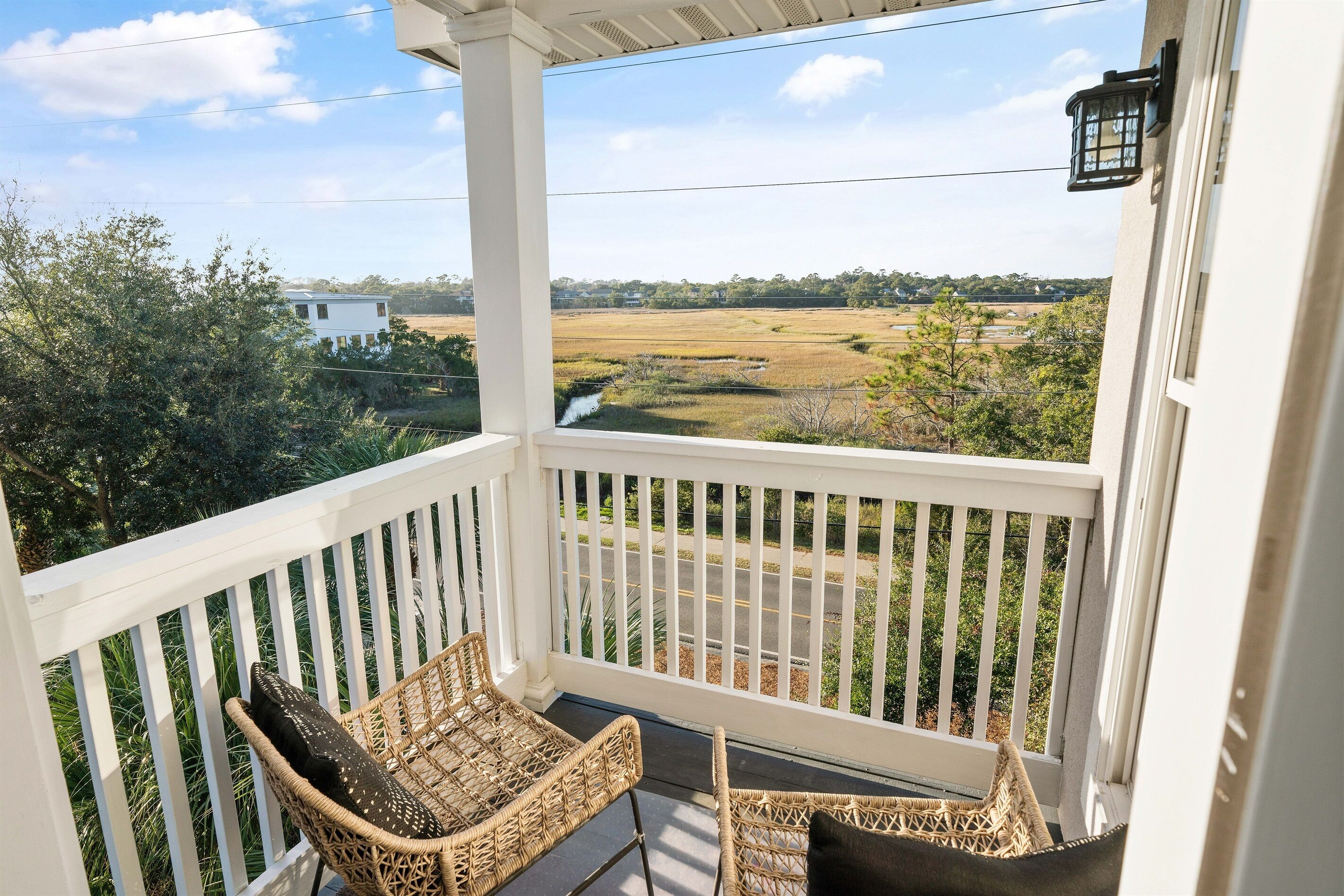 A porch with wicker furniture and a view of a rural landscape.