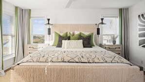 Ein Schlafzimmer mit einem Bett, zwei Nachttischen, einem Deckenventilator und einem Fenster mit Vorhängen.