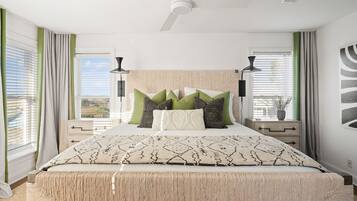 A bedroom with a bed, two bedside tables, a ceiling fan, and a window with curtains.