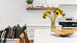 Eine moderne Küche mit weißen Schränken, einem Holztisch und einer Vase mit Sonnenblumen.