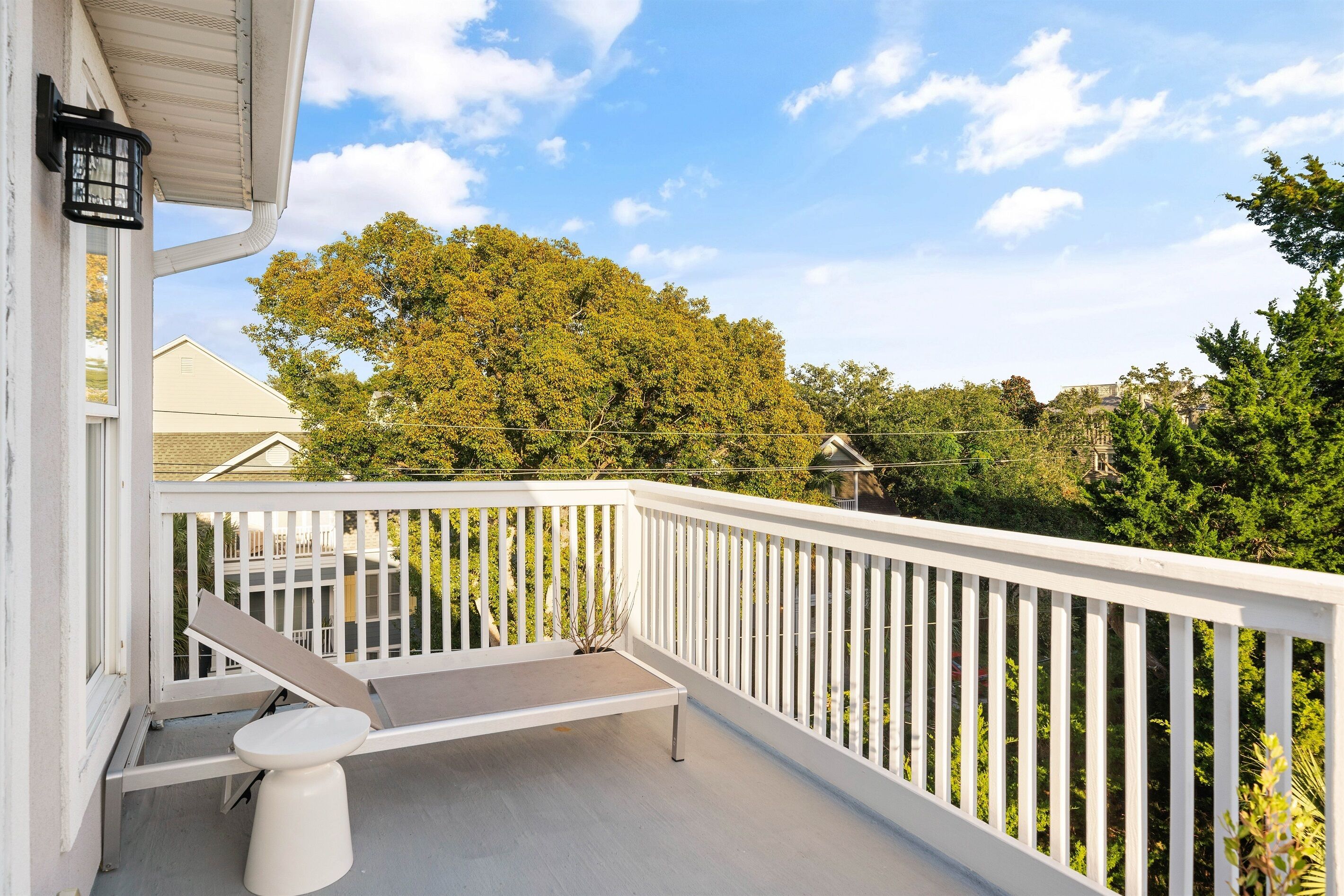 A balcony with a white railing, a bench, and a small table.