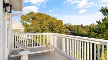 A balcony with a white railing, a bench, and a small table.