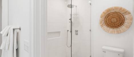 Ein modernes Badezimmer mit einer gläsernen Duschkabine, einer Toilette und einer dekorativen Wandgestaltung aus gewebtem Material.