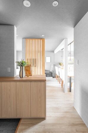 Un interior moderno con un mostrador de recepción de madera, una planta en maceta y un panel de madera corredero.