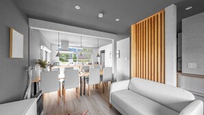 A modern living room with a white sofa, a dining area with a wooden table and chairs, and a kitchen in the background. - THE ARBANO (Furano)