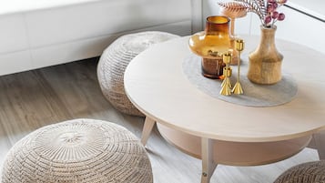 Un salón moderno con un sofá blanco, una mesa de centro redonda y otomanas tejidas.