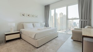 A modern bedroom with a large bed, a nightstand, a chair, and a view of the city through large windows. - La Vie Residence - JBR Dubai (Dubai)