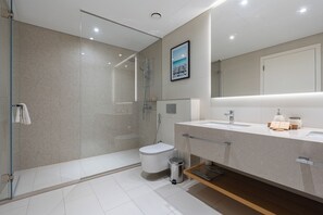 A modern bathroom with a glass-enclosed shower, a toilet, and a vanity with a mirror.