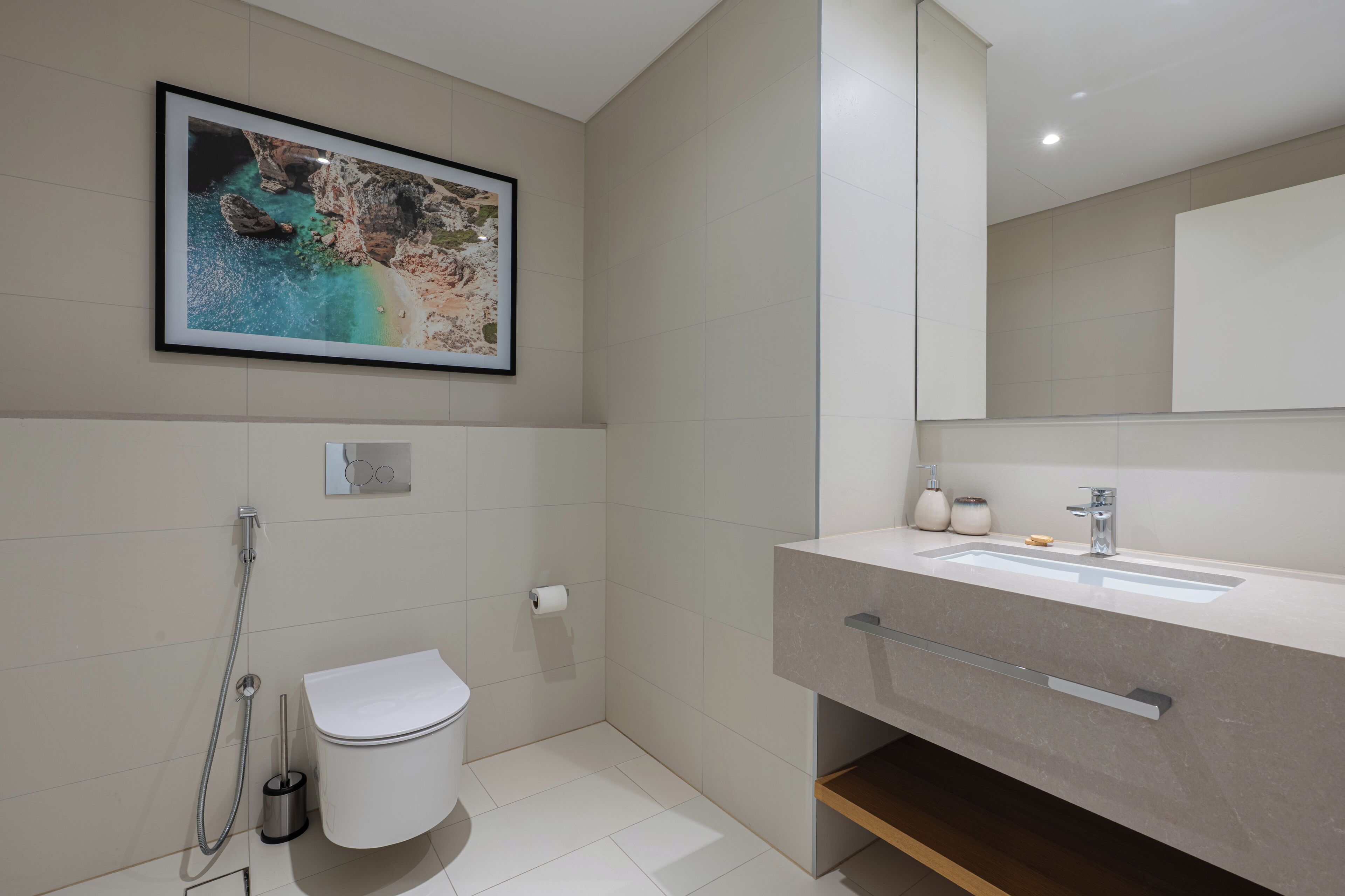Une salle de bain moderne avec un grand miroir, un lavabo et des toilettes.