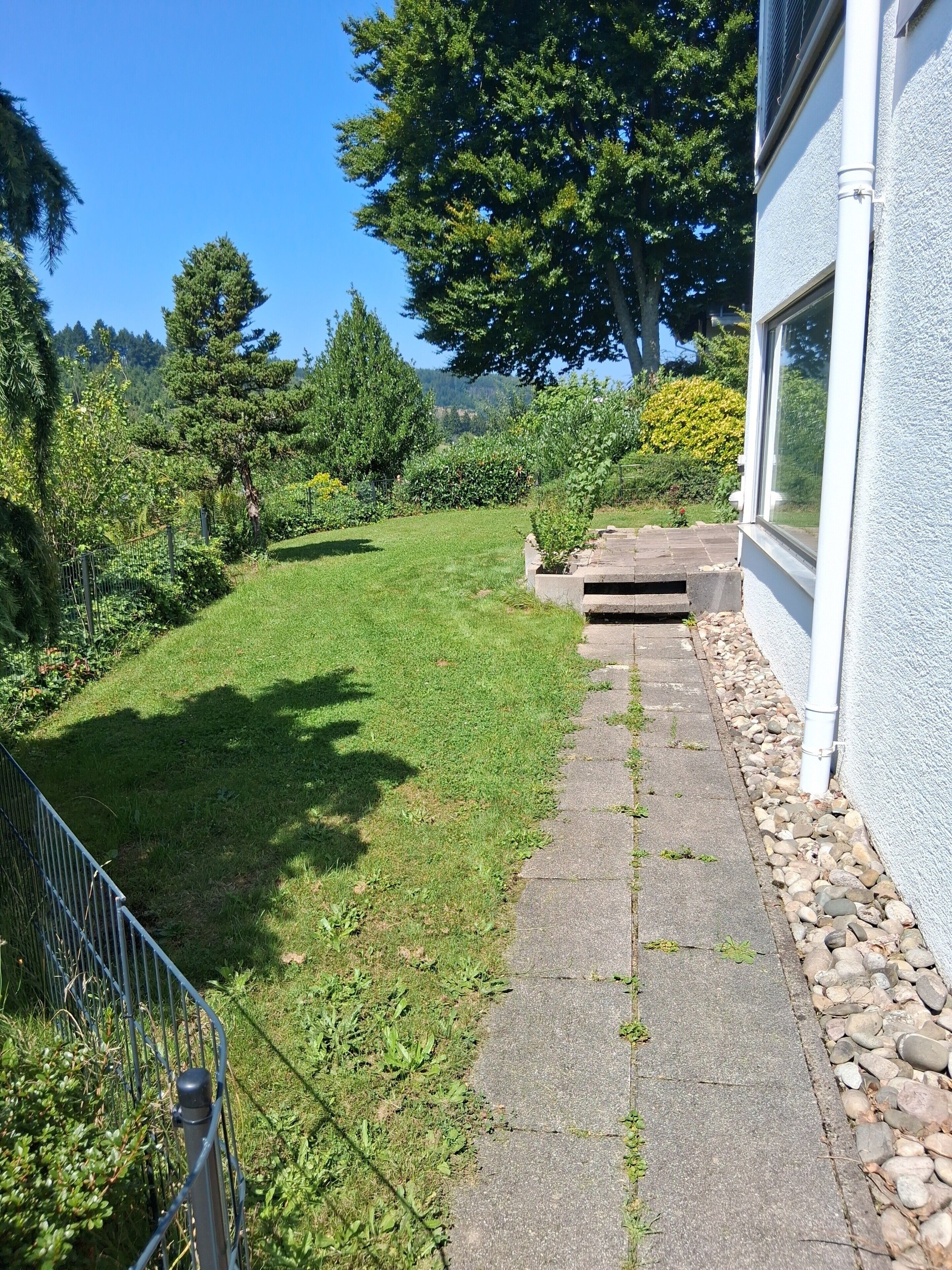A well-maintained lawn, a stone pathway, and a metal fence.