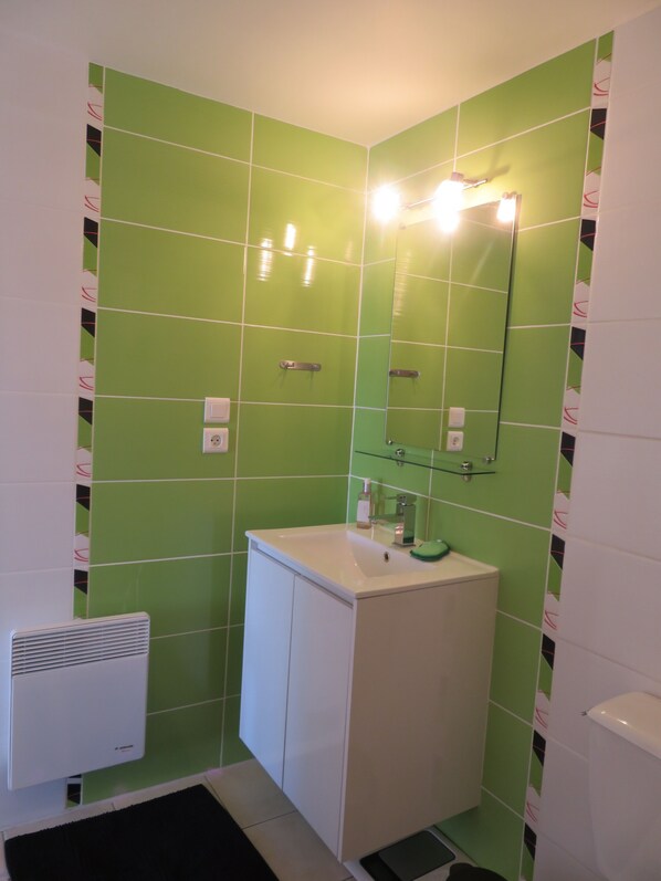A bathroom with green tiles, a white sink, and a mirror. - COLUMBIA (Concorès)