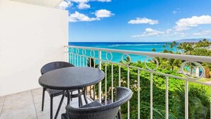 A balcony with a view of the ocean and palm trees.