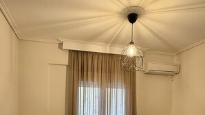 A living room with a sofa, a wooden table with two chairs, a TV, and a ceiling fan. - Domus Philippi–Spacious Stay the Heart of Larisa, Perfect for Families & Friends (Larisa)