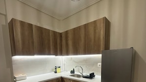 A modern kitchen with wooden cabinets, a stainless steel refrigerator, and a white countertop. - Domus Philippi–Spacious Stay the Heart of Larisa, Perfect for Families & Friends (Larisa)