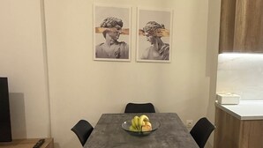 A dining area with a table, chairs, and two framed pictures on the wall. - Domus Philippi–Spacious Stay the Heart of Larisa, Perfect for Families & Friends (Larisa)