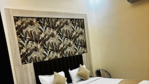 A modern bedroom with a bed, bedside tables, a ceiling fan, and an air conditioning unit. - Hotel La Serene (Agra)
