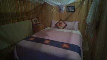 Una habitación con una cama, una mesita de noche, un cuadro enmarcado y un dosel.