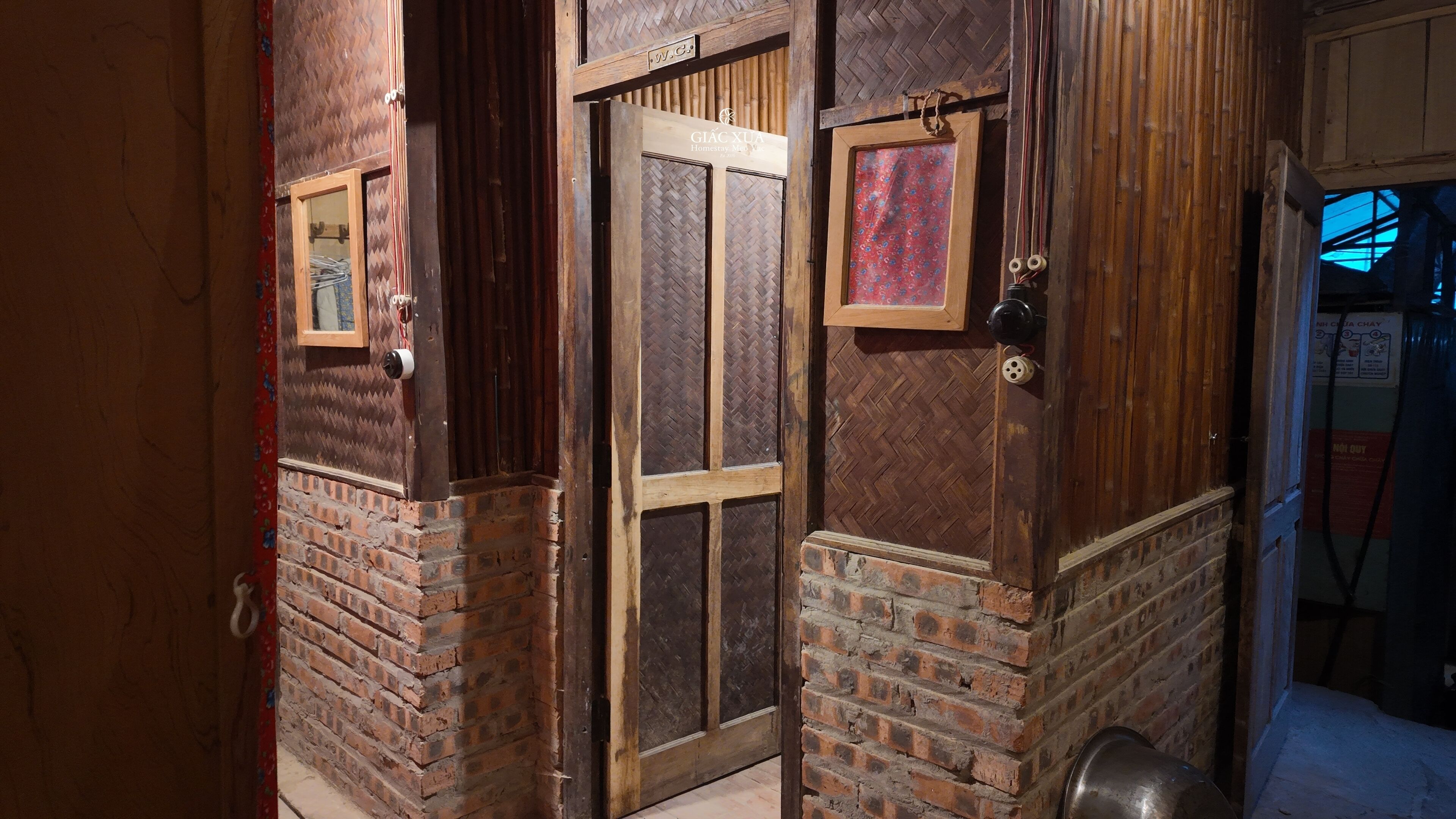 A wooden door with a glass panel, a brick wall, and a small sign above the door.