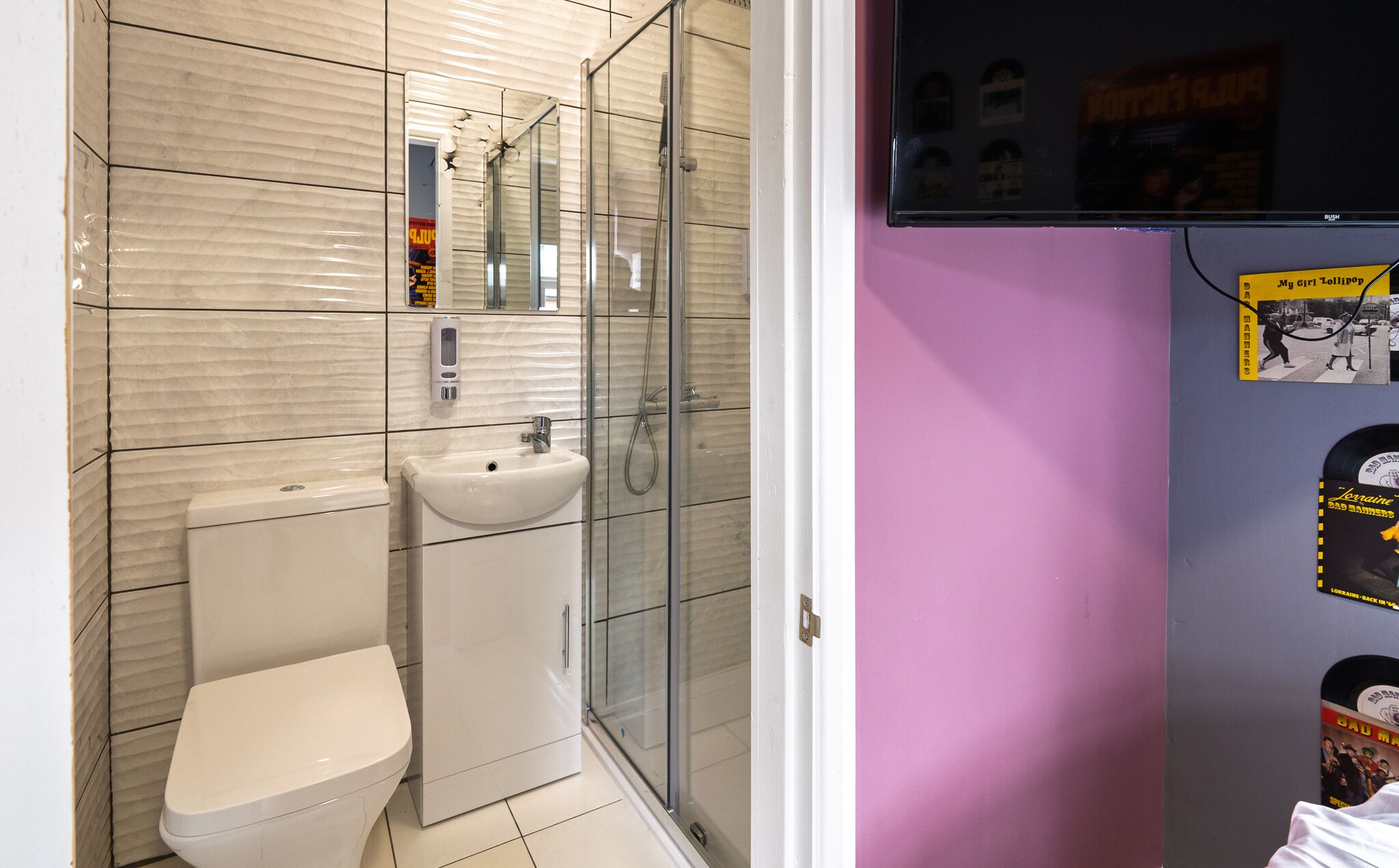 A bathroom with a toilet, sink, and glass shower enclosure.