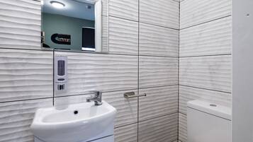 A modern bathroom with a white sink, a mirror, and a toilet.
