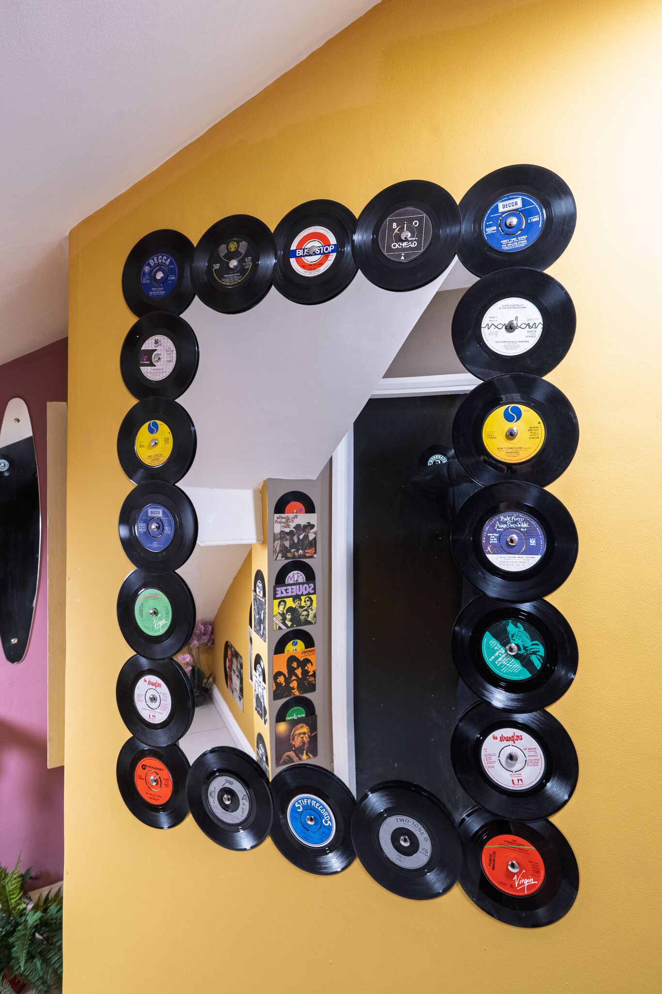 A wall with a collection of vinyl records arranged in a semi-circular pattern.