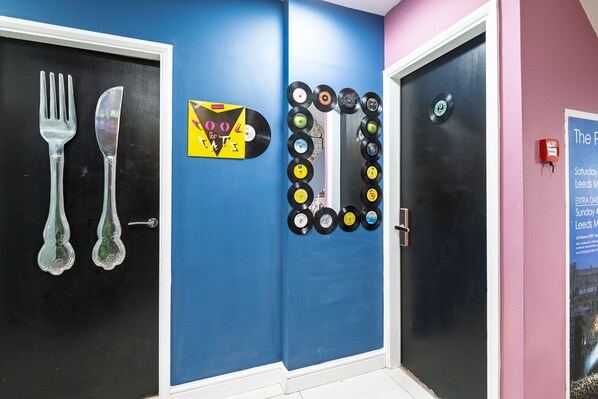 A hallway with a blue wall, a door with a record player, and a poster advertising an event. - Starbeck Micro Hotel (Harrogate)