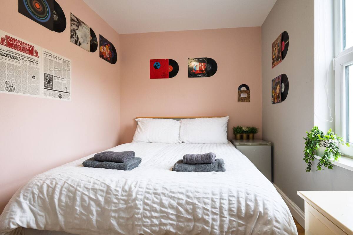 A bedroom with a bed, pillows, and a wall decorated with vinyl records.