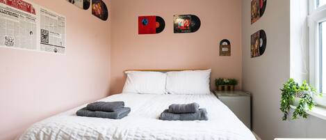 Un dormitorio con una cama, almohadas y una pared decorada con discos de vinilo.