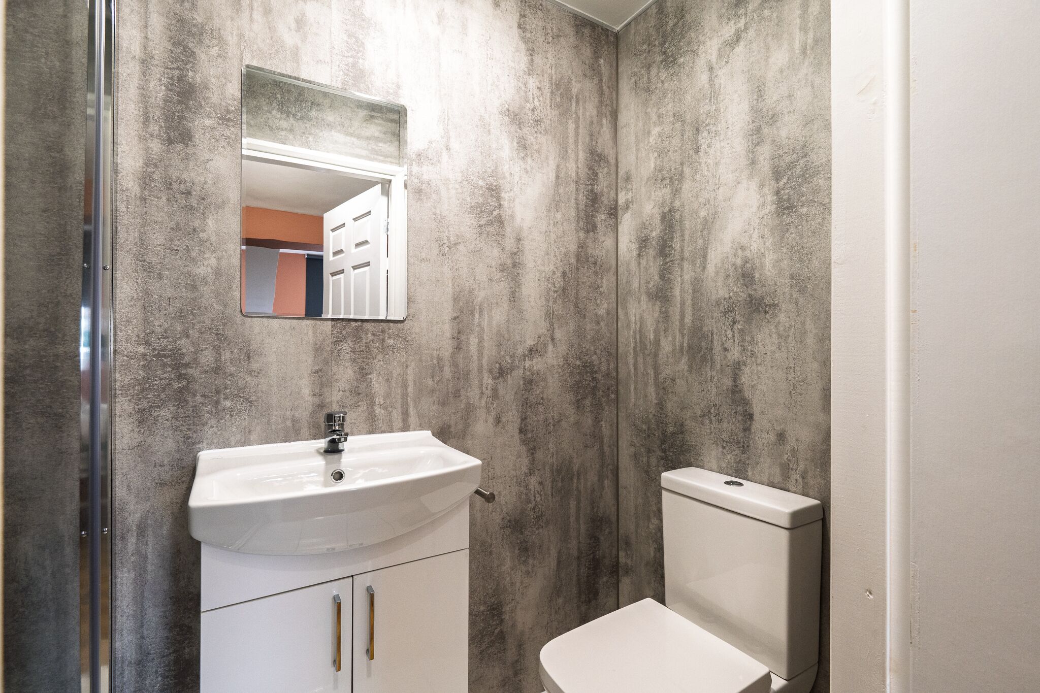 Un baño con lavamanos blanco, un espejo y un inodoro.