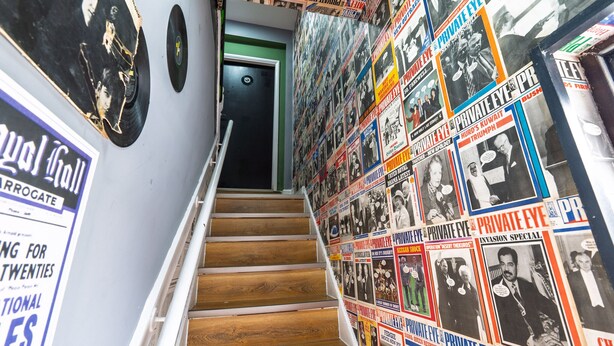 Uma escadaria com cartazes e um disco de vinil na parede.