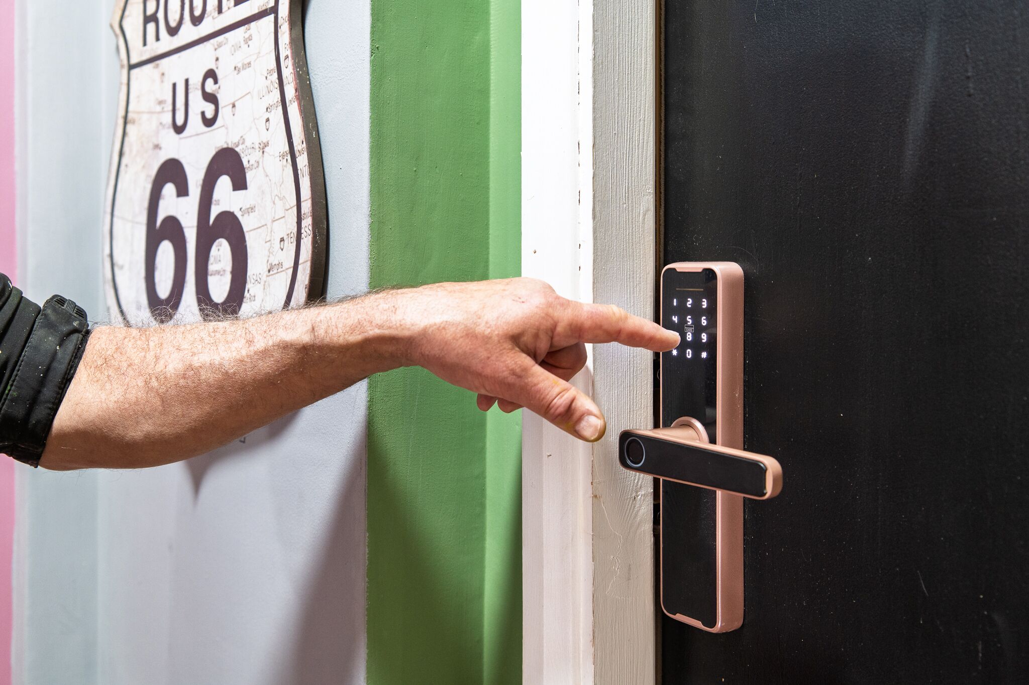 A hand using a smartphone to interact with a door lock.