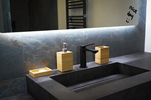 A modern bathroom with a large mirror, a black faucet, and wooden soap dispensers.