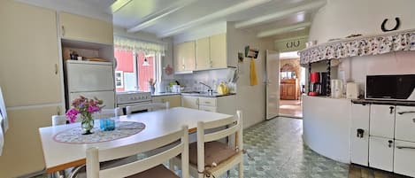 A compact kitchen with a dining table, chairs, a refrigerator, a stove, and a microwave.