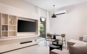 Un salon moderne avec un téléviseur à écran plat, une table à manger, des chaises et un canapé.
