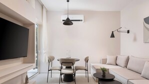 A modern living room with a flat-screen TV, a dining table with chairs, a sofa, a coffee table, and a pendant light. - Glyfada Prime Apartment, Glyfada Prime Living (Athens)