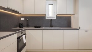 Eine moderne Küche mit Einbauofen, Kaffeemaschine und Spüle.