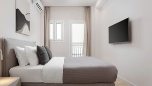 Ein modernes Schlafzimmer mit einem Bett, einem Flachbildfernseher und einem Fenster mit Vorhängen.