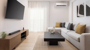Ein modernes Wohnzimmer mit Flachbildfernseher, einer Couch, einem Couchtisch und einer Holz-Unterhaltungsecke.