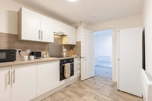 Une cuisine moderne avec des meubles blancs, un four à micro-ondes, un four et un réfrigérateur.